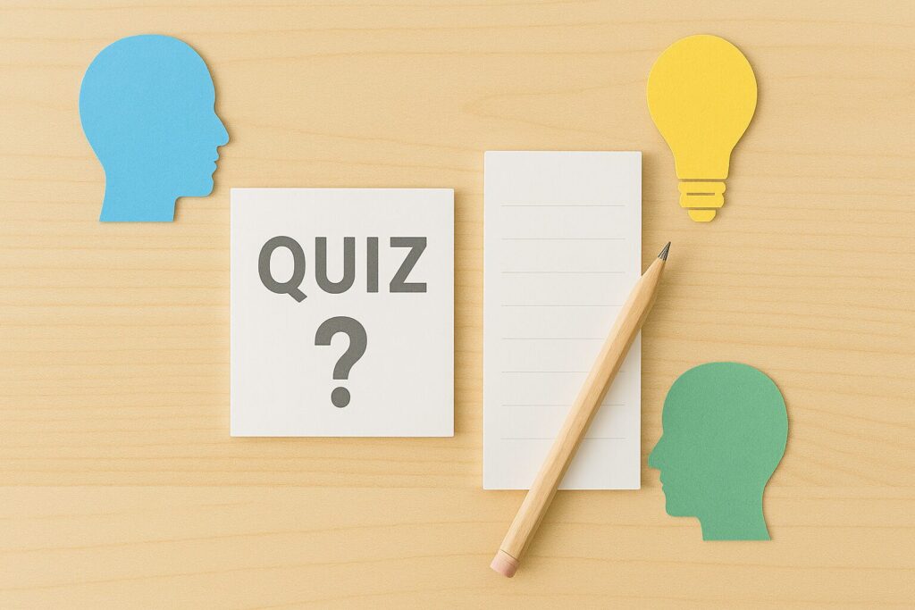 机の上に“QUIZ？”と書かれたカードと鉛筆、メモ用紙、そして人の横顔と電球の形をしたカラフルな紙が並べられている。