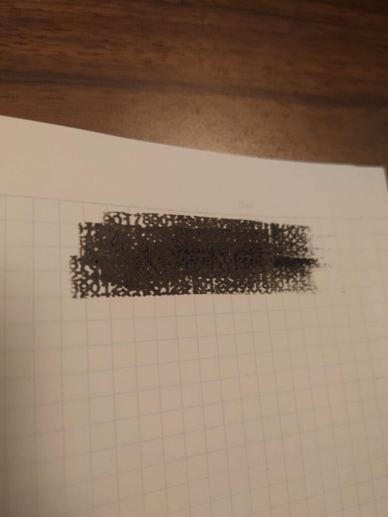 ダイソー個人情報保護スタンプ黒ダブルローラータイプをボールペン文字の上に押した検証写真。文字が黒いパターンで見えにくくなっている様子。